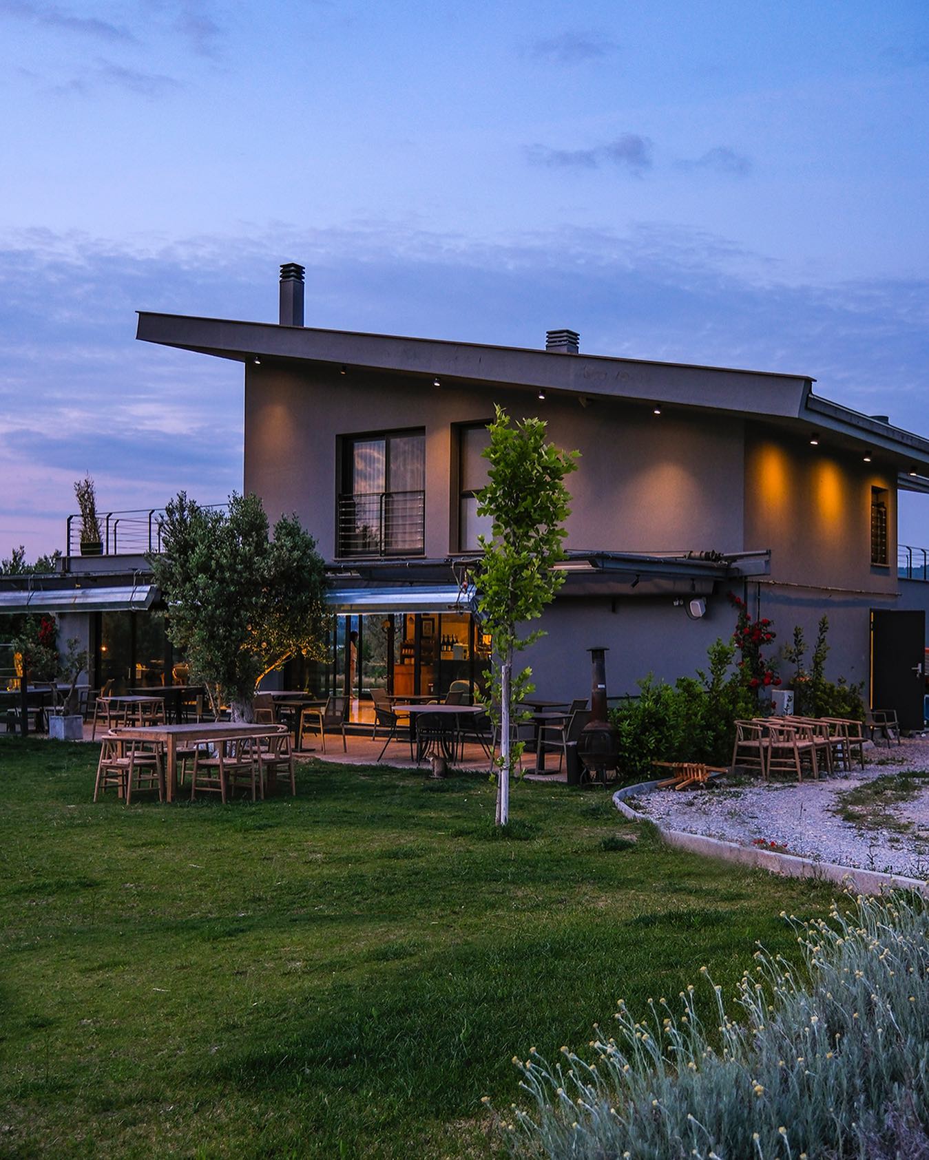 Modern Turkish winery building illuminated at dusk with outdoor seating